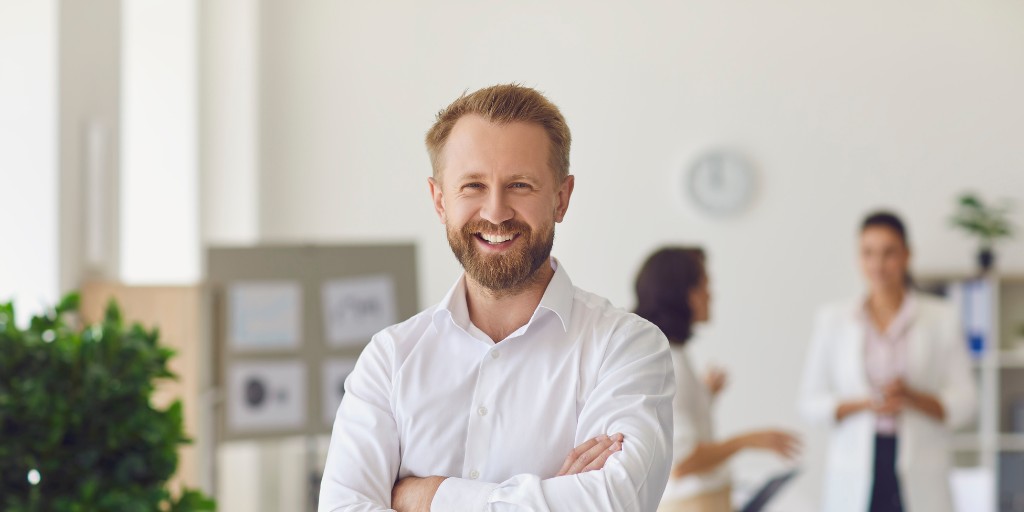 Man in work shirt smiling at the camera with his arms crossed over his chest