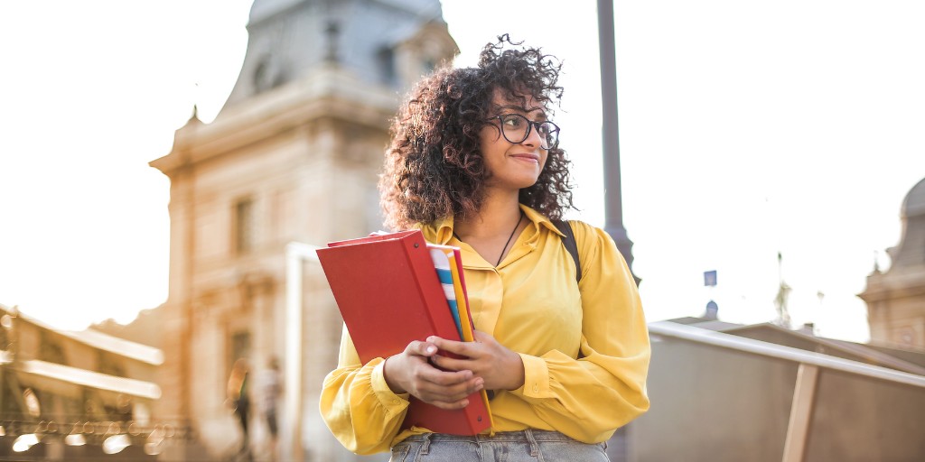 Female student holding books and smiling away from the camera